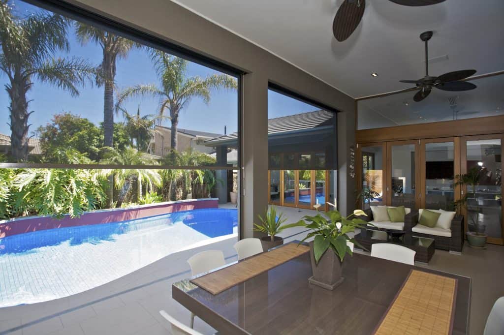 Indoor-outdoor living area with dining table and pool view.