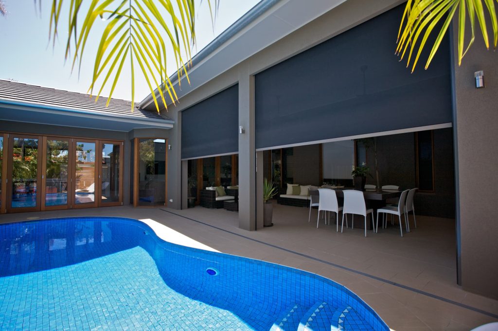 Modern patio with pool, dining set, seating, and retractable shades.