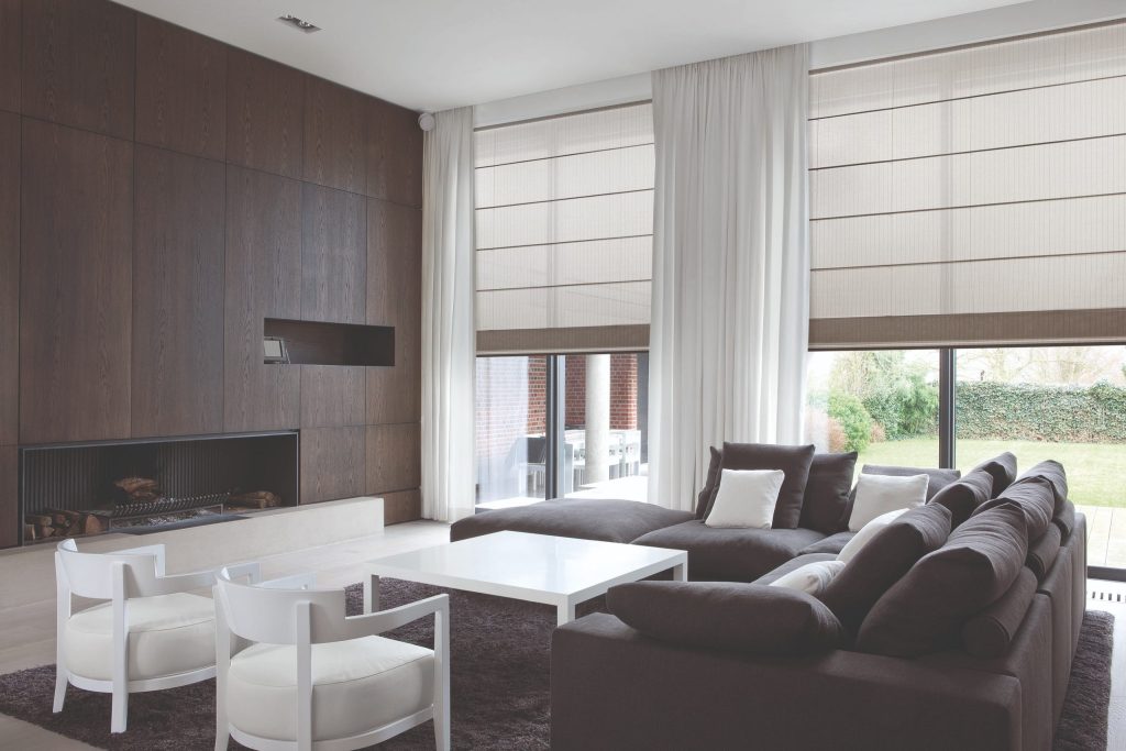 Modern living room with dark sofa, fireplace, and large windows.
