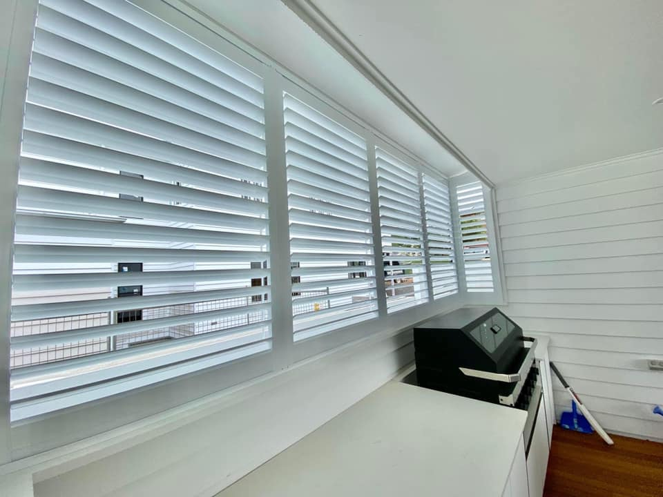Bright room with shutters, white counter, and dark wood floor.