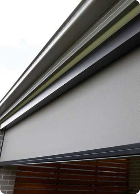 Close-up view of a modern retractable outdoor blind installed on a building, partially extended, with metal housing and fabric panel.
