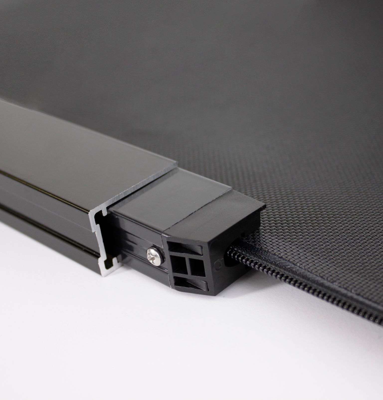 Close-up of a black metal and plastic frame corner with a screw and a textured panel on a white surface.