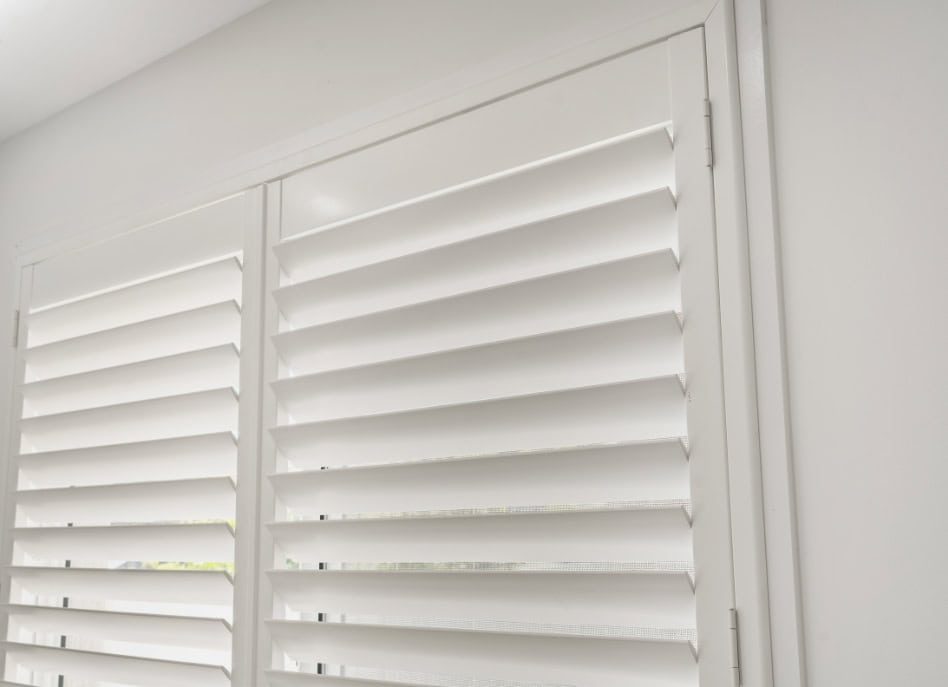 Indoor PVC shutters open, letting soft light filter through.