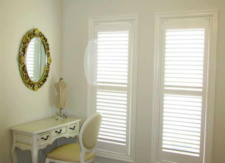 Bedroom corner with vanity, white shutters, and chandelier.
