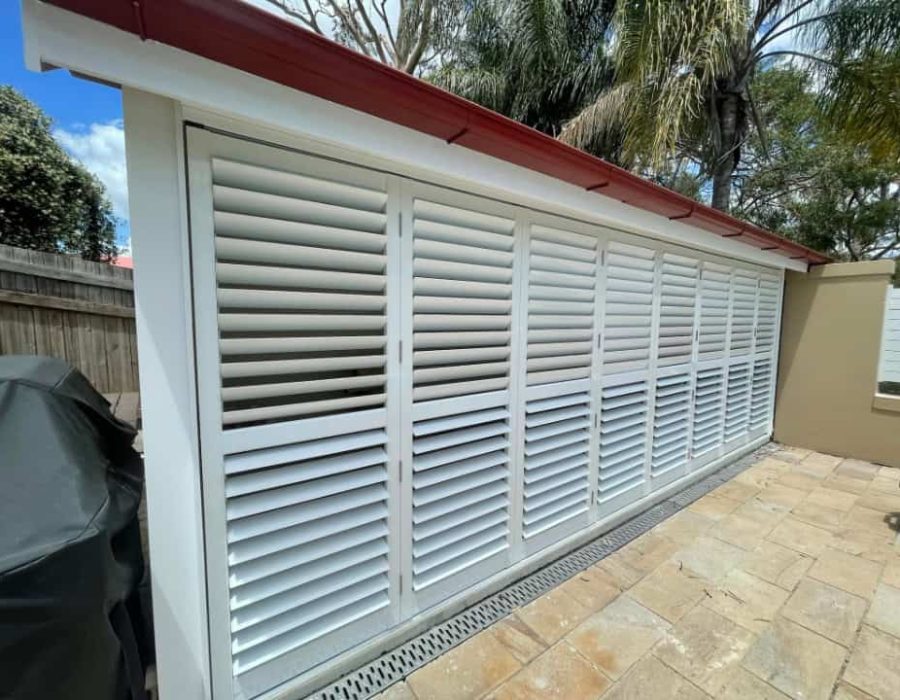 White aluminum shutter door, red roof, palm trees, and grill.