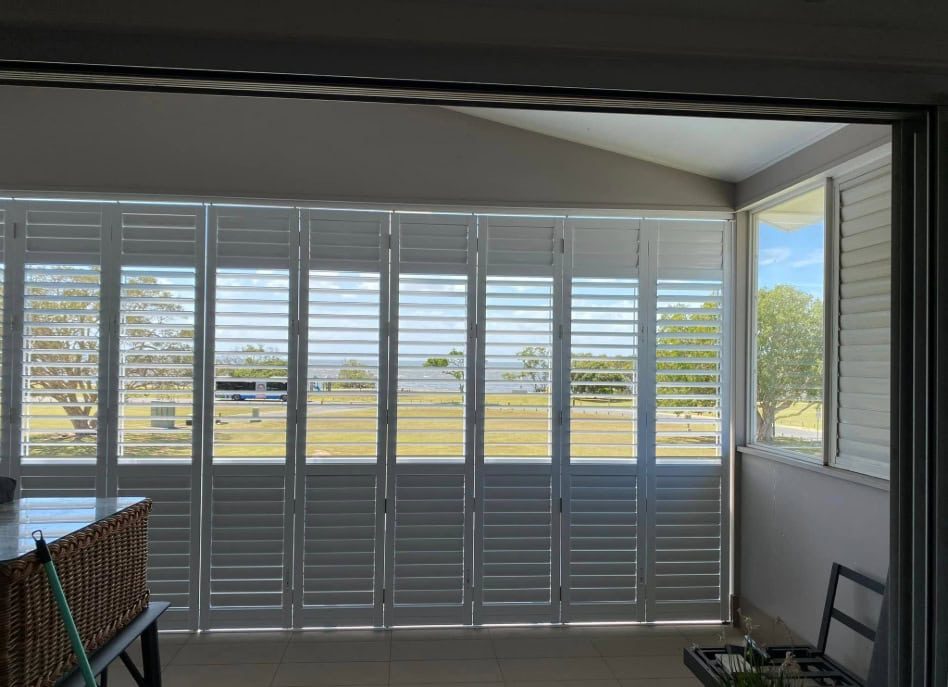 Sunlit room with aluminum shutters, wicker basket, and table.