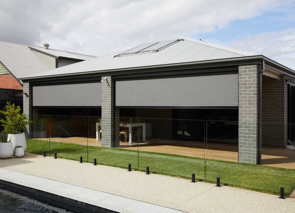 Modern house with gray brick exterior, patio, and pool view.